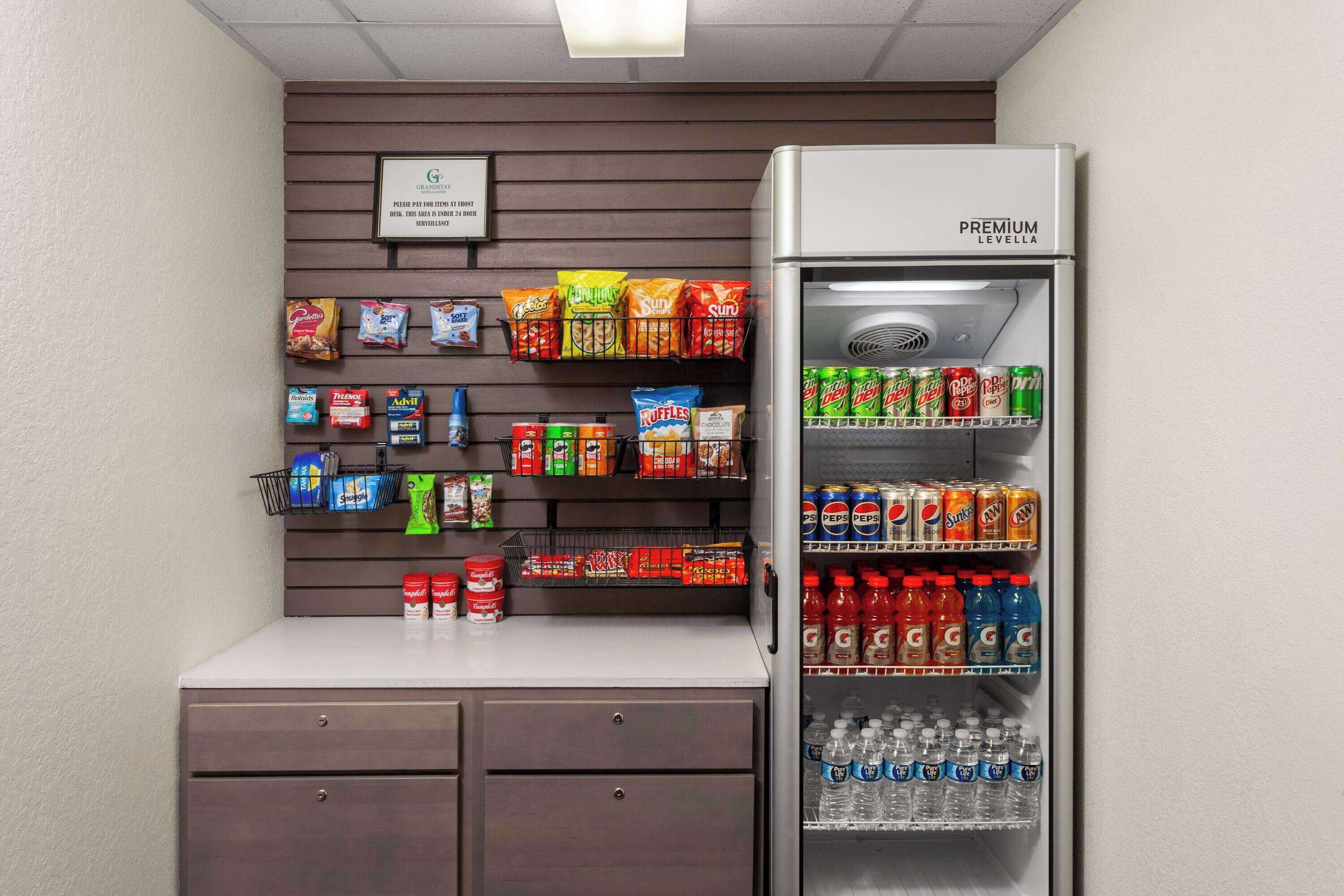 A kitchenette with a refrigerator stocked with beverages and snacks, a microwave, and a small countertop with drawers.
