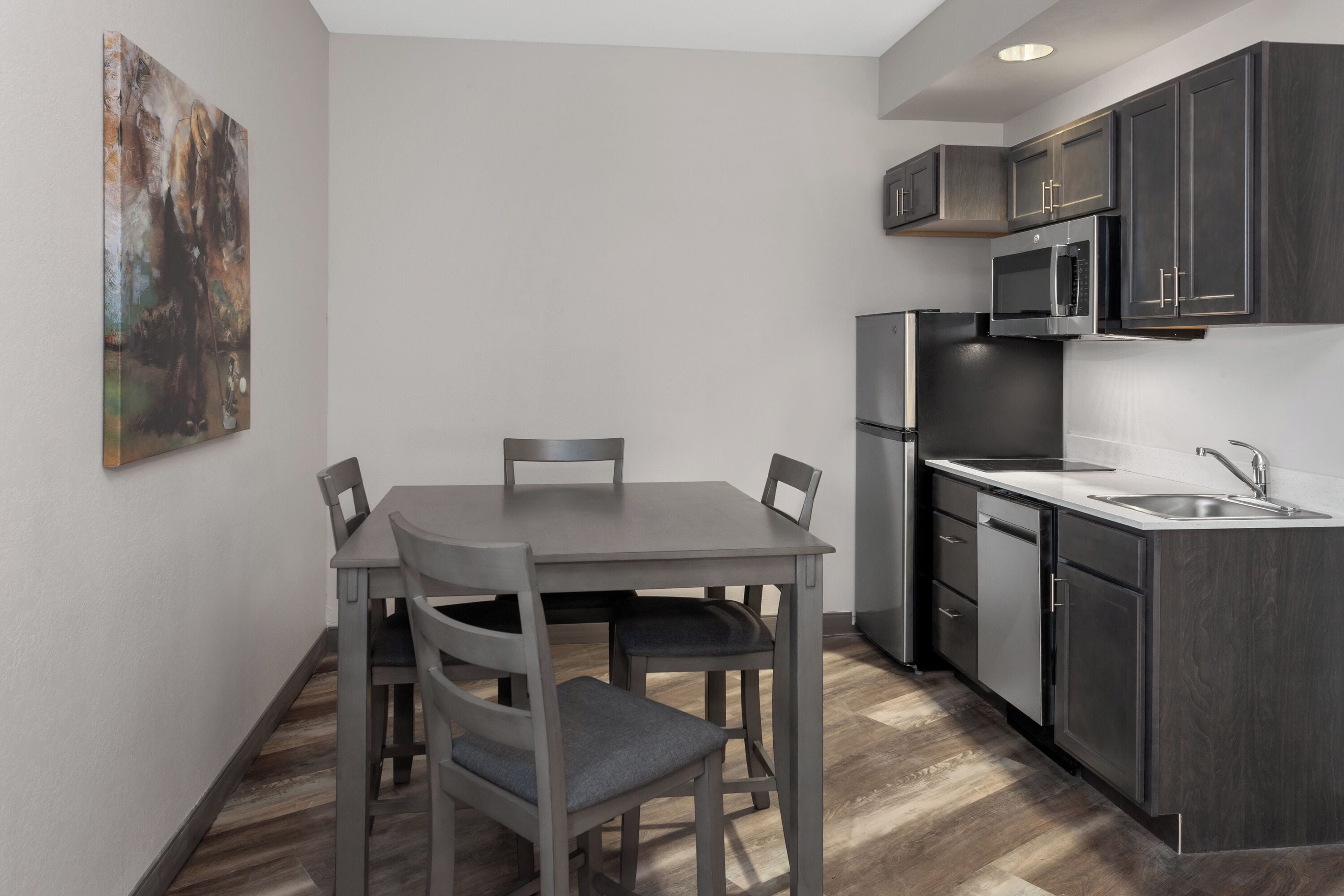 A modern kitchen with dark cabinets, a stainless steel refrigerator, and a microwave.