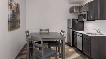 A compact kitchen with dark cabinets, a stainless steel refrigerator, and a microwave.