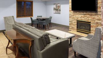 Una sala de estar moderna con un sofá, una mesa de comedor, sillas, un televisor y una chimenea.