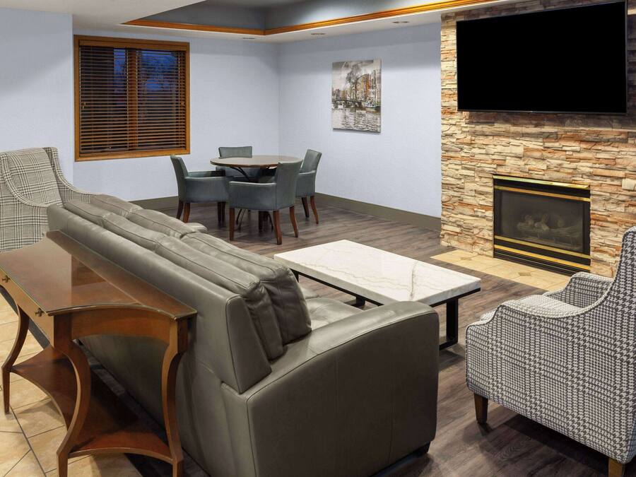 A modern living room with a sofa, dining table, chairs, a TV, and a fireplace.