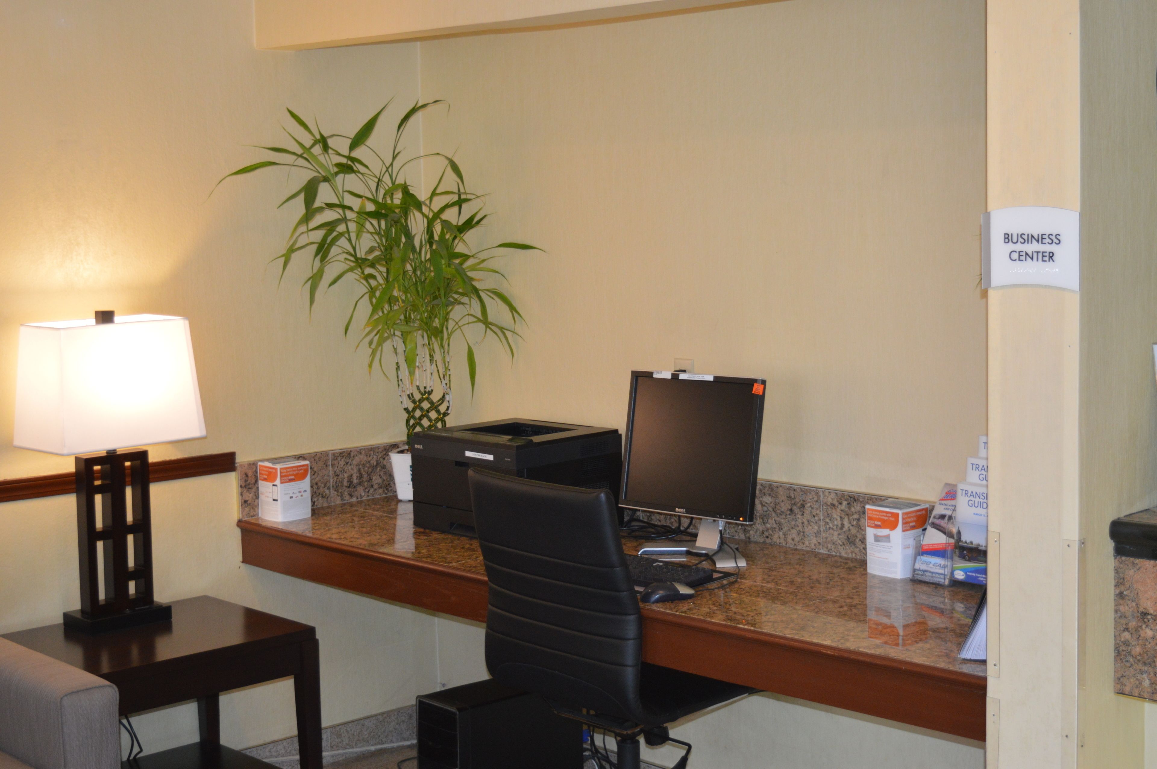 A reception desk with a computer, printer, and a plant.