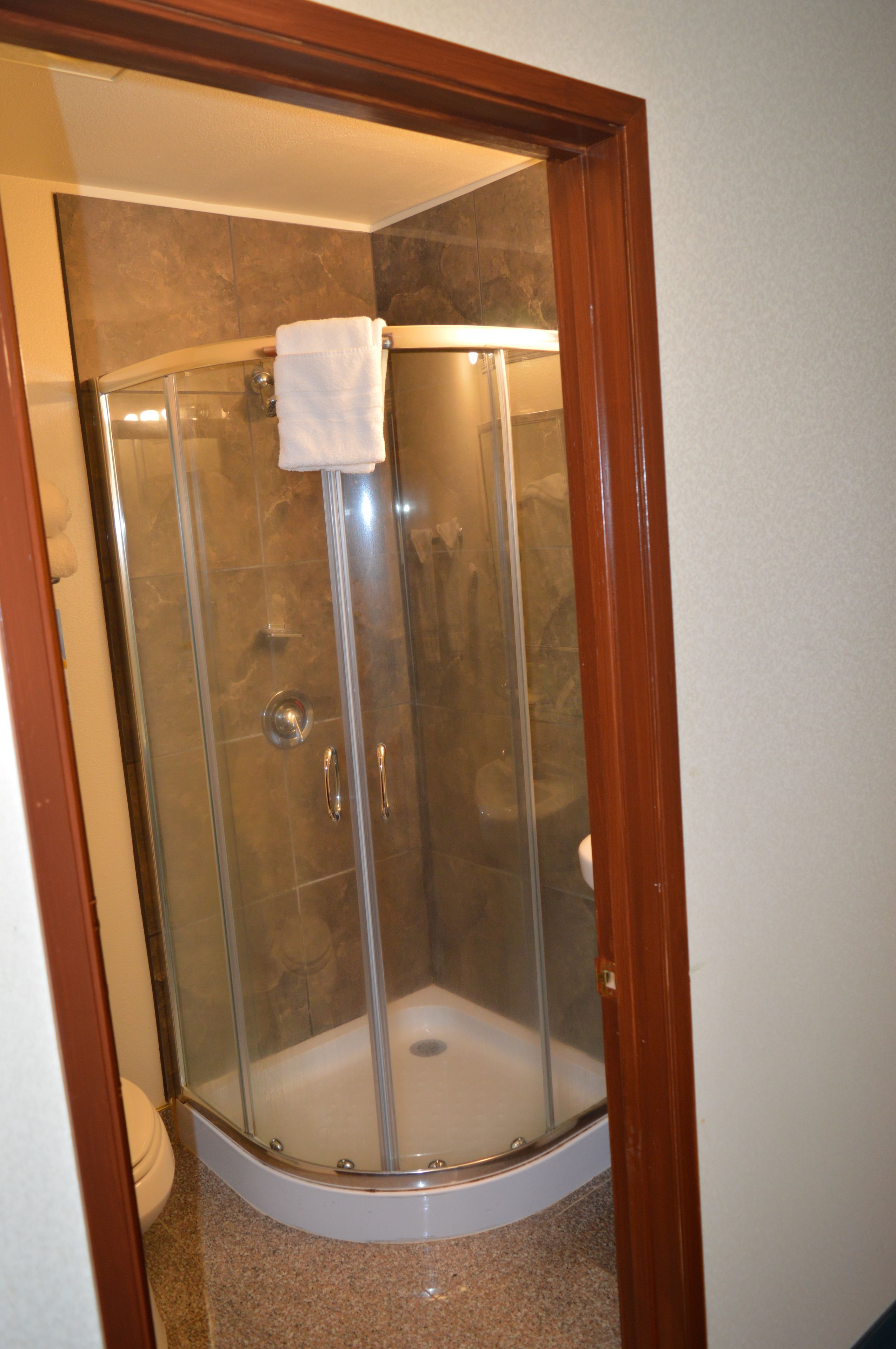 A glass-enclosed shower stall with a white towel hanging on the door handle.