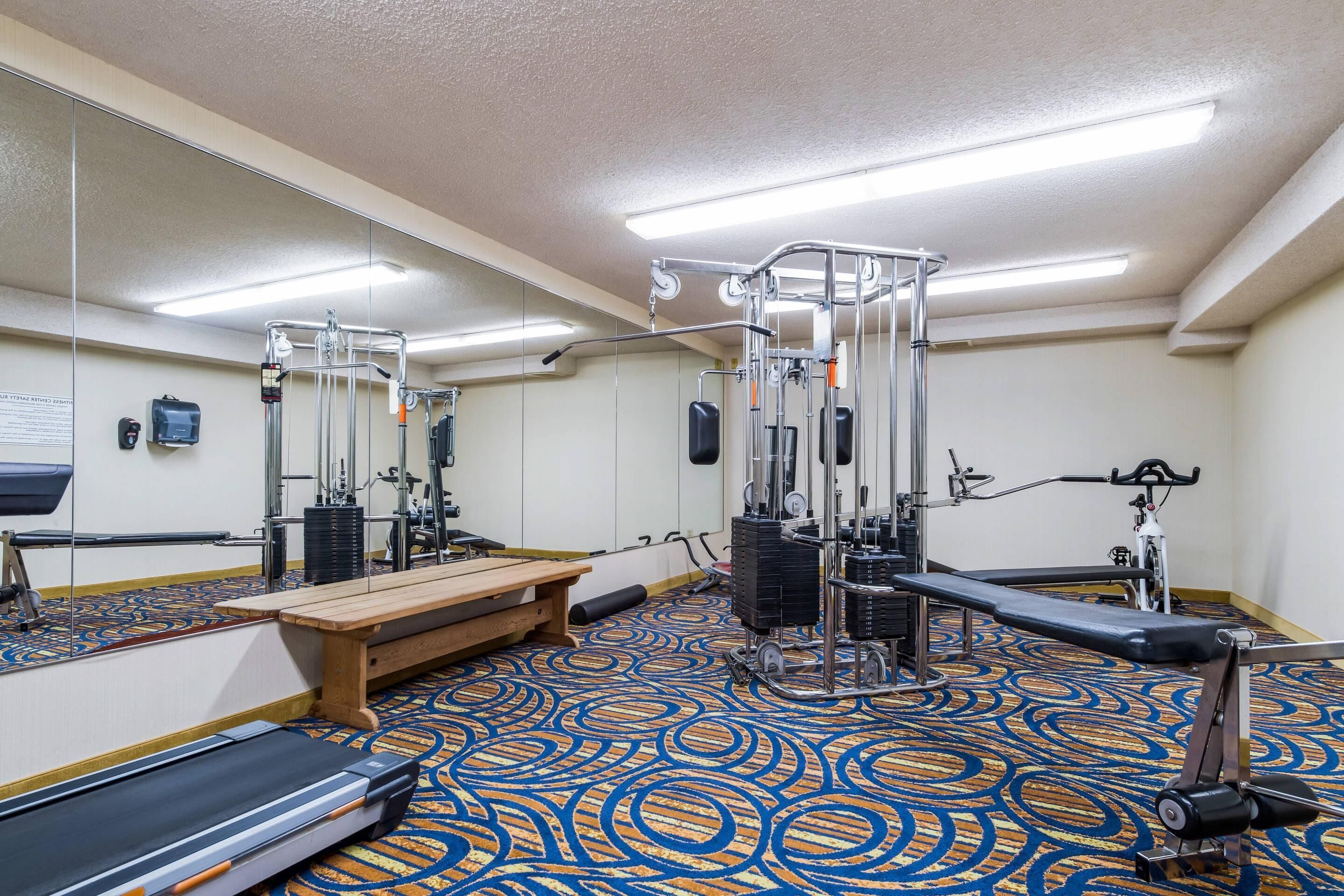 Un gimnasio con equipamiento de ejercicio, una cinta de correr y un espejo grande.