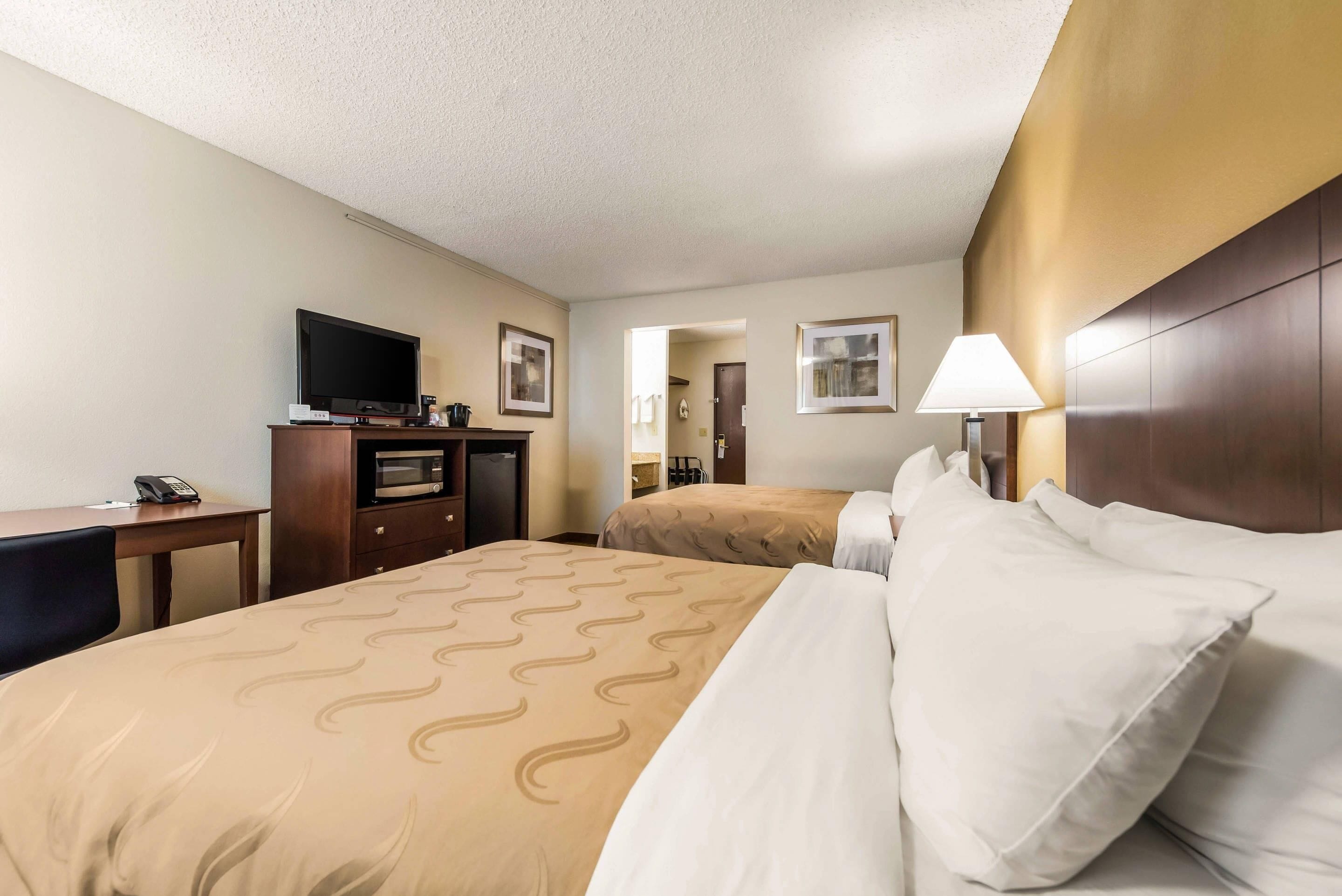 A hotel room with a bed, a desk, a television, and a lamp.