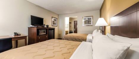 A hotel room with a bed, a desk, a television, and a lamp.