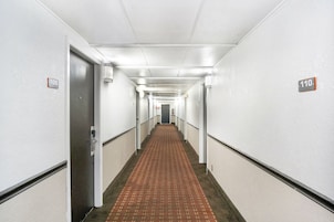 Un pasillo de hotel con puertas numeradas 109 y 110, suelo alfombrado y paredes blancas.