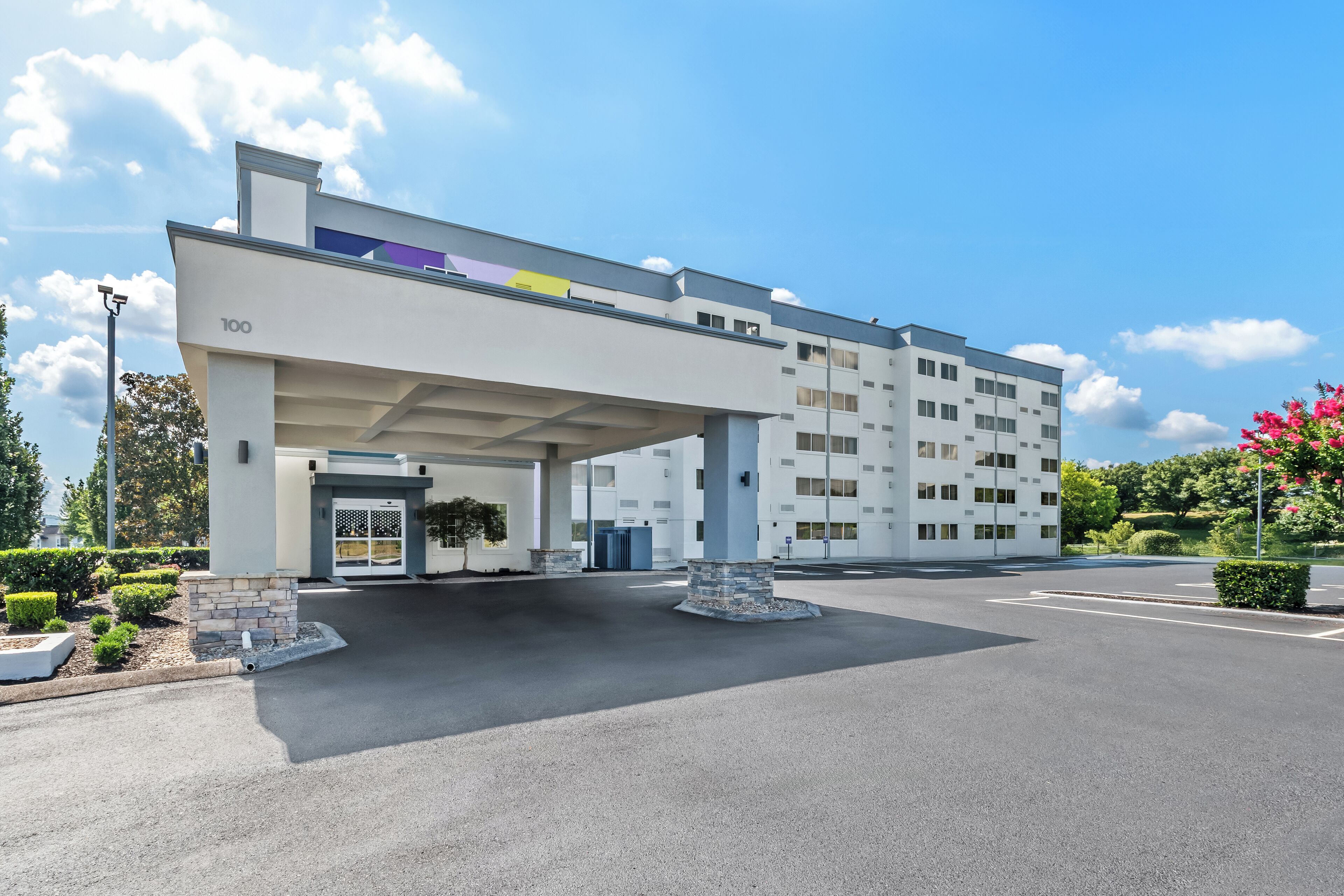 Un hotel modern amb teulada plana, entrada coberta i una zona d'aparcament.