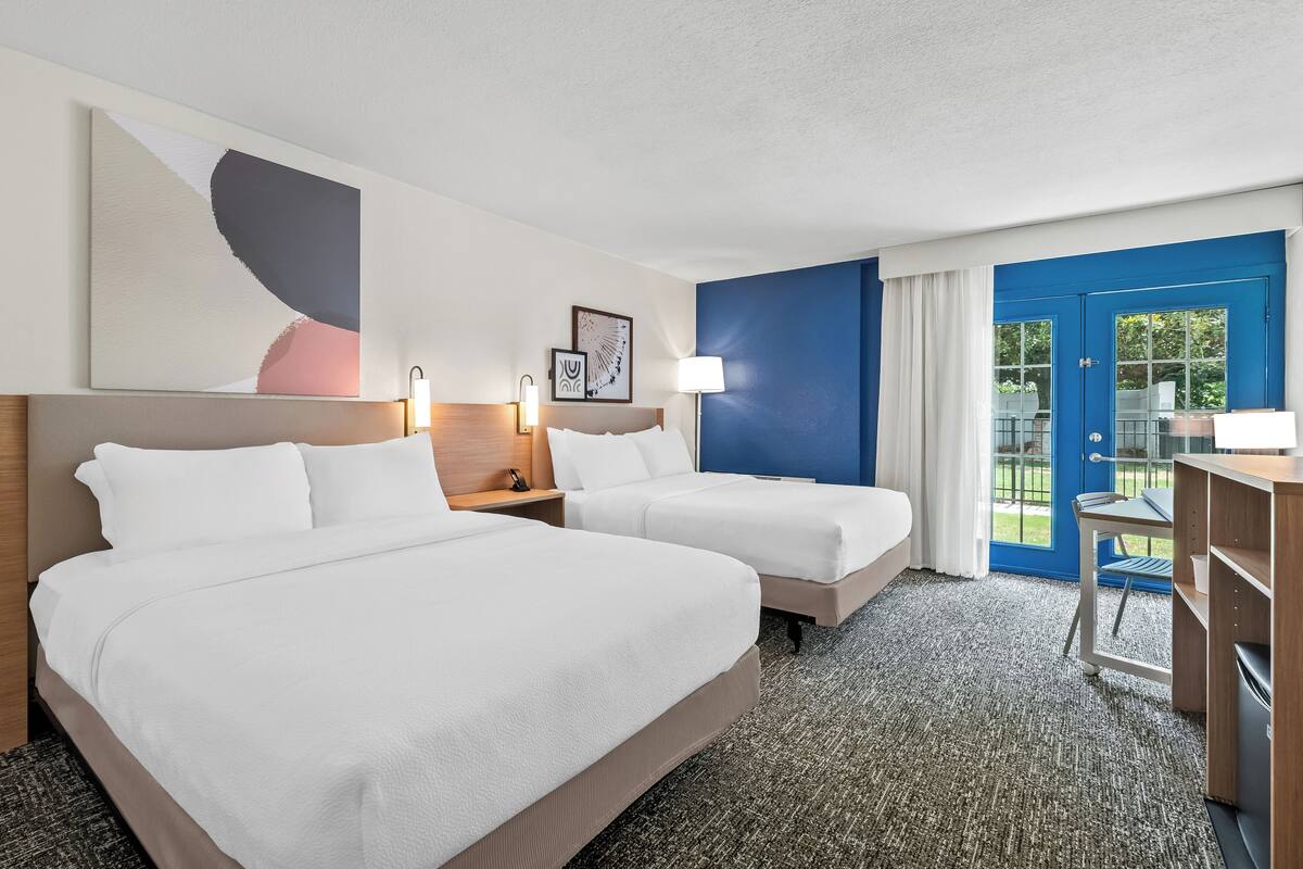 Ein Hotelzimmer mit zwei Betten, einem Schreibtisch und einem Stuhl.
