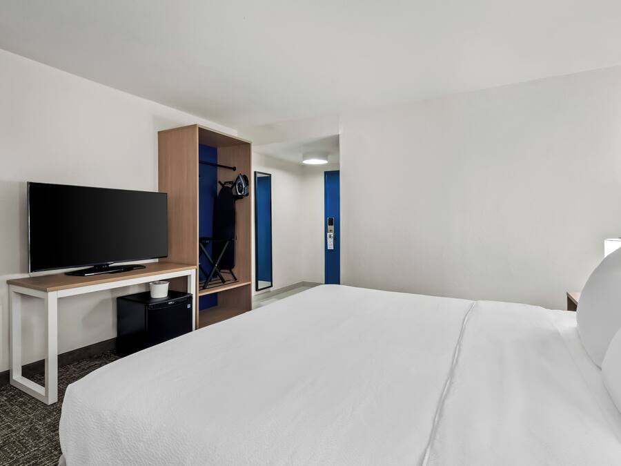 Une chambre d’hôtel avec un lit, un téléviseur posé sur un meuble, un bureau et une armoire.