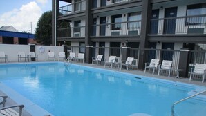 A swimming pool with lounge chairs and a multi-story building in the background. - Motel 6 Chattanooga, TN - Airport (Chattanooga)