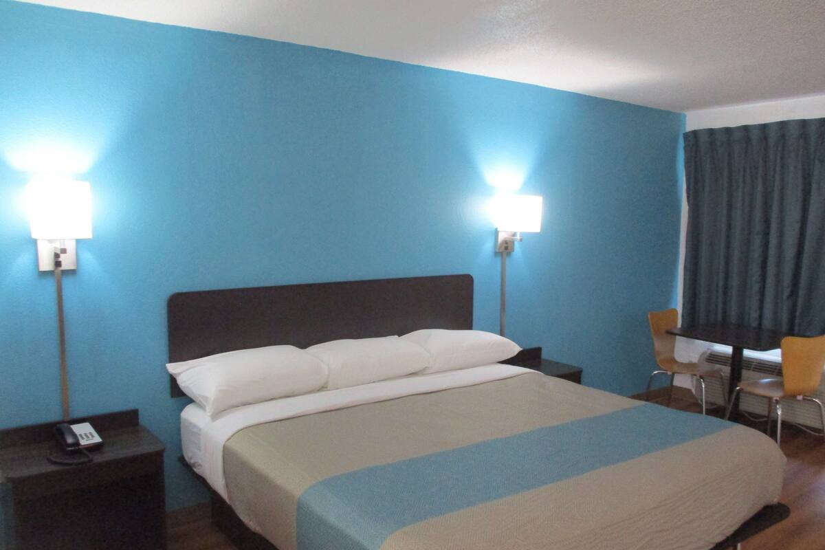 A hotel room with a bed, bedside tables, a desk, and a chair.