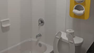 A bathroom with a bathtub, toilet, and a towel rack with three towels.
