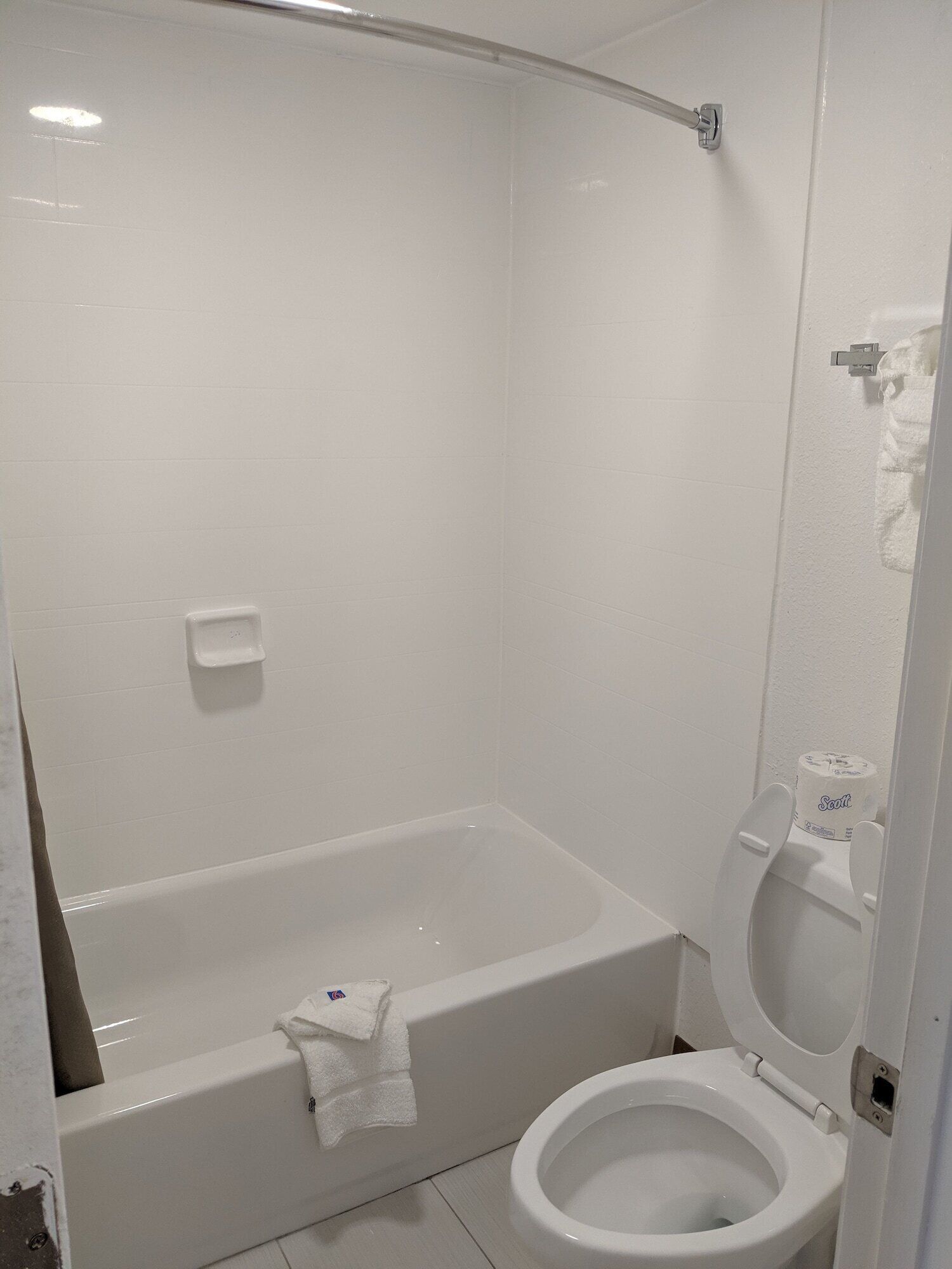 Un baño con bañera, inodoro y un perchero para toallas.