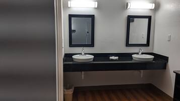 Baño con dos lavamanos, encimeras negras y un espejo sobre cada uno.