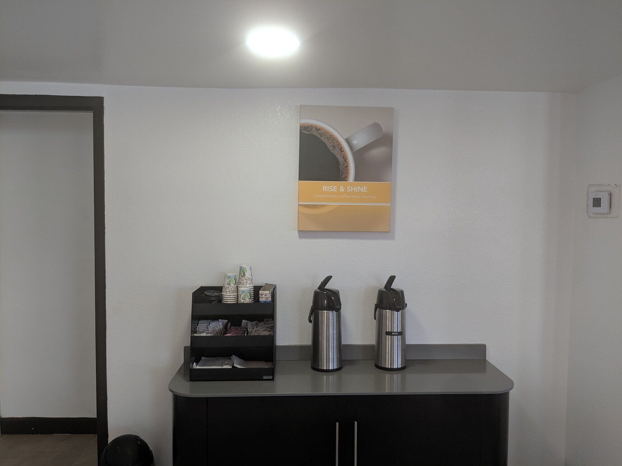 A small kitchenette area with a coffee machine, a kettle, and a coffee dispenser on a counter.