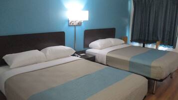 Habitación de hotel con dos camas, una mesita de noche, una lámpara y una ventana con cortinas.