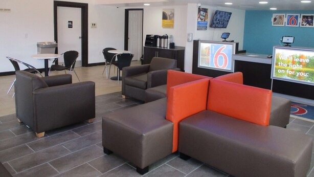 A hotel lobby with seating areas, a reception desk, and a digital display. - Motel 6 Chattanooga, TN - Airport (Chattanooga)