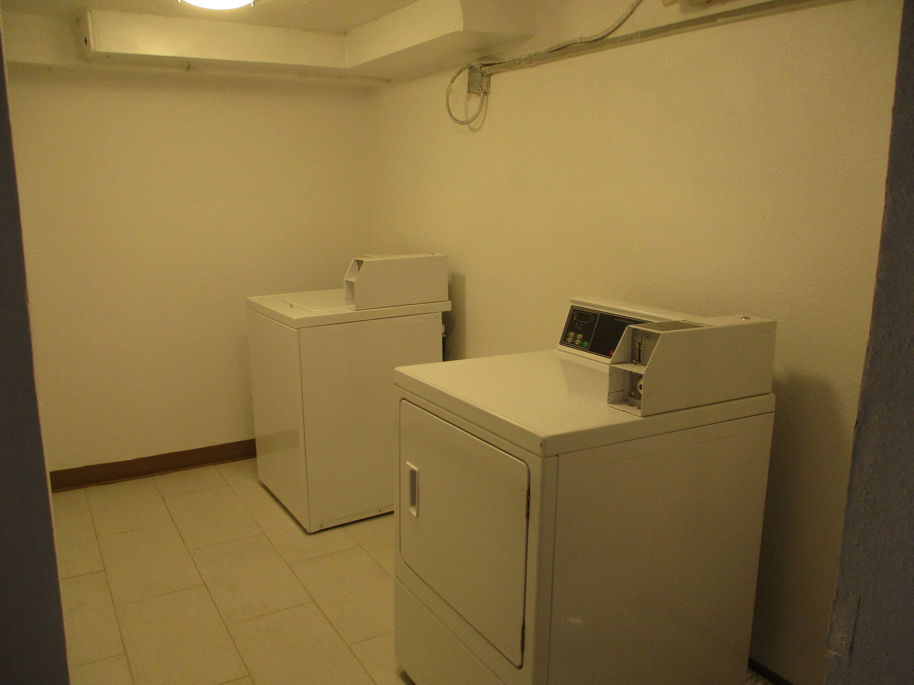 A laundry room with two white washing machines and a dryer.