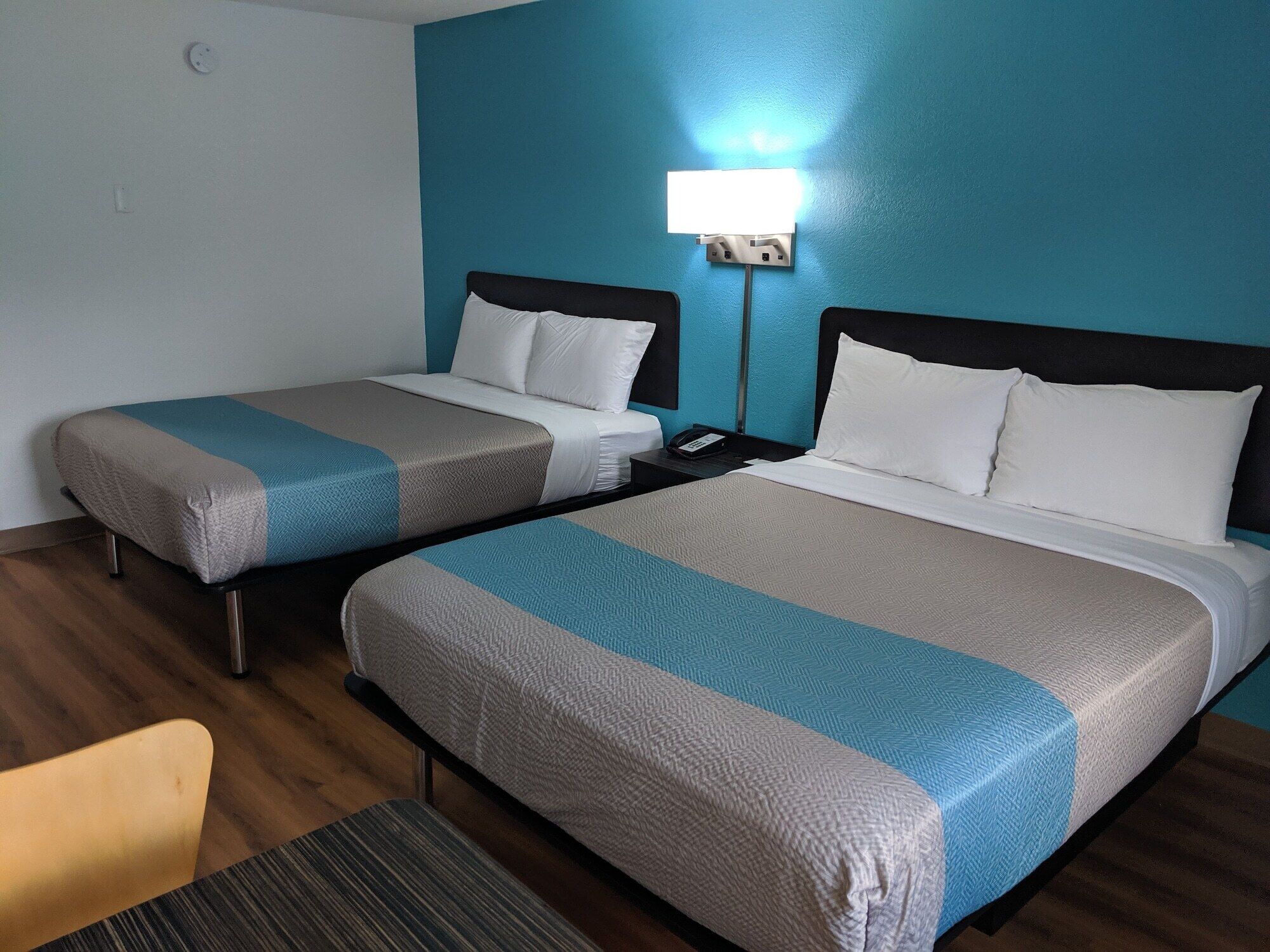 Une chambre d’hôtel avec deux lits, chacun recouvert d’une couverture bleue et beige, agrémentée d’oreillers blancs et dotée d’une table de chevet avec un téléphone.