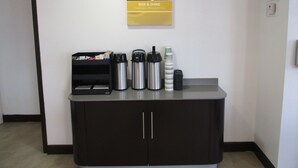A hotel reception area with a coffee station featuring a coffee machine, cups, and a thermos. - Motel 6 Chattanooga, TN - Airport (Chattanooga)