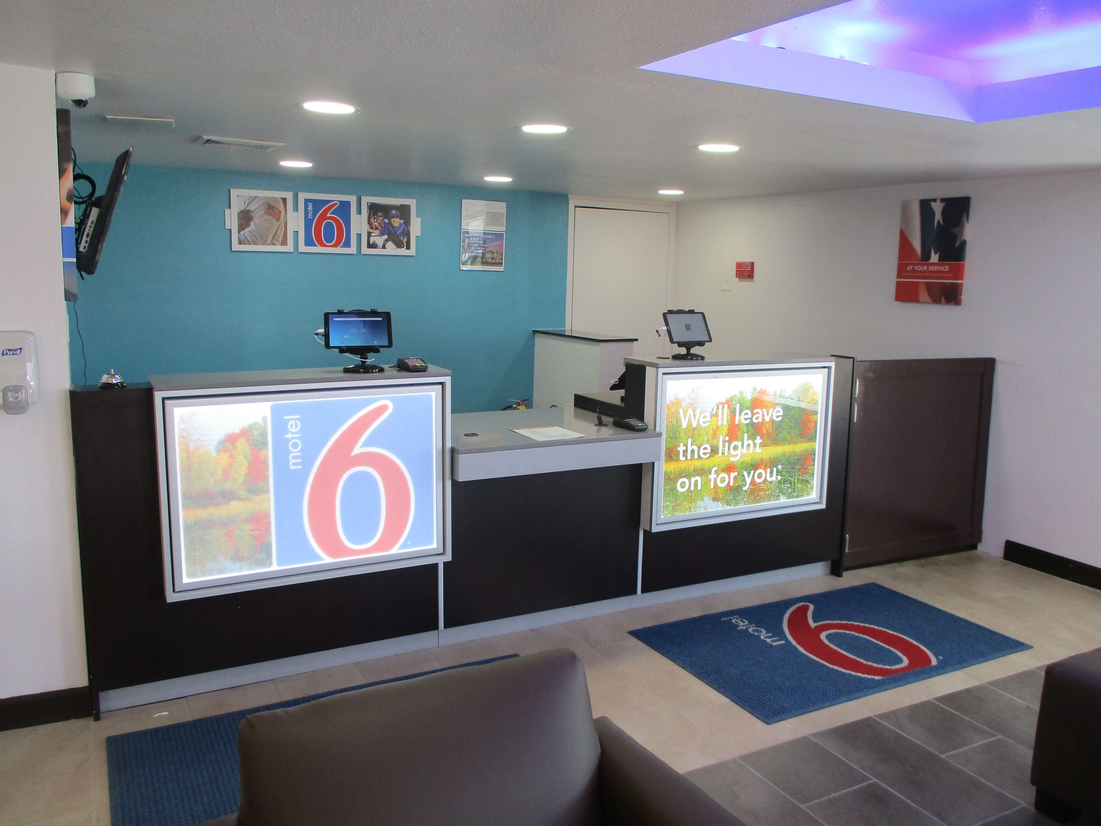 A hotel reception area with a blue wall, a reception desk, and a digital display.