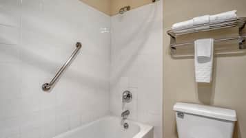 Ein Badezimmer mit Badewanne, Toilette, Handlauf und Handtuchhalter.