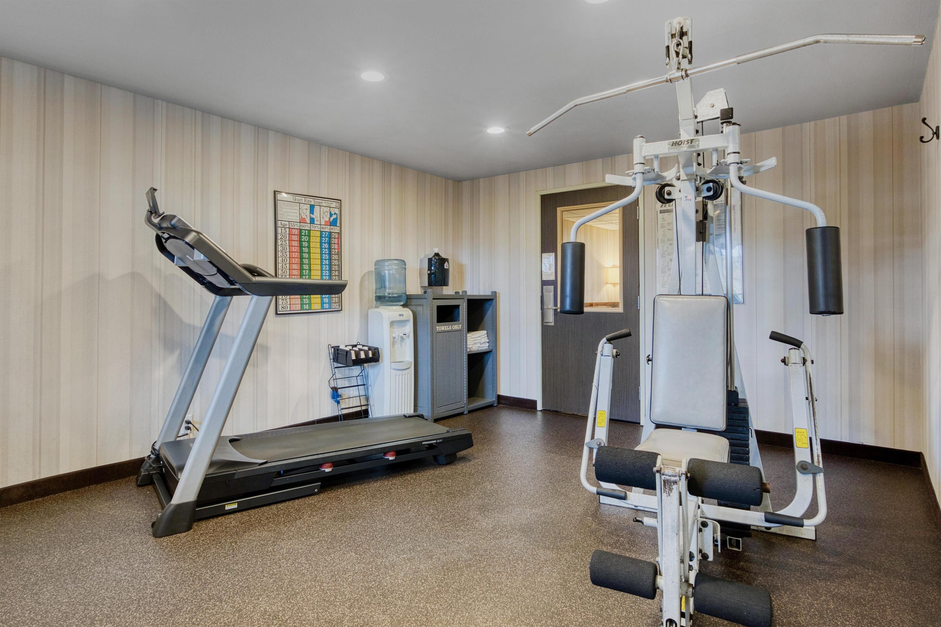 A gym with a treadmill, weight machines, and a water dispenser.