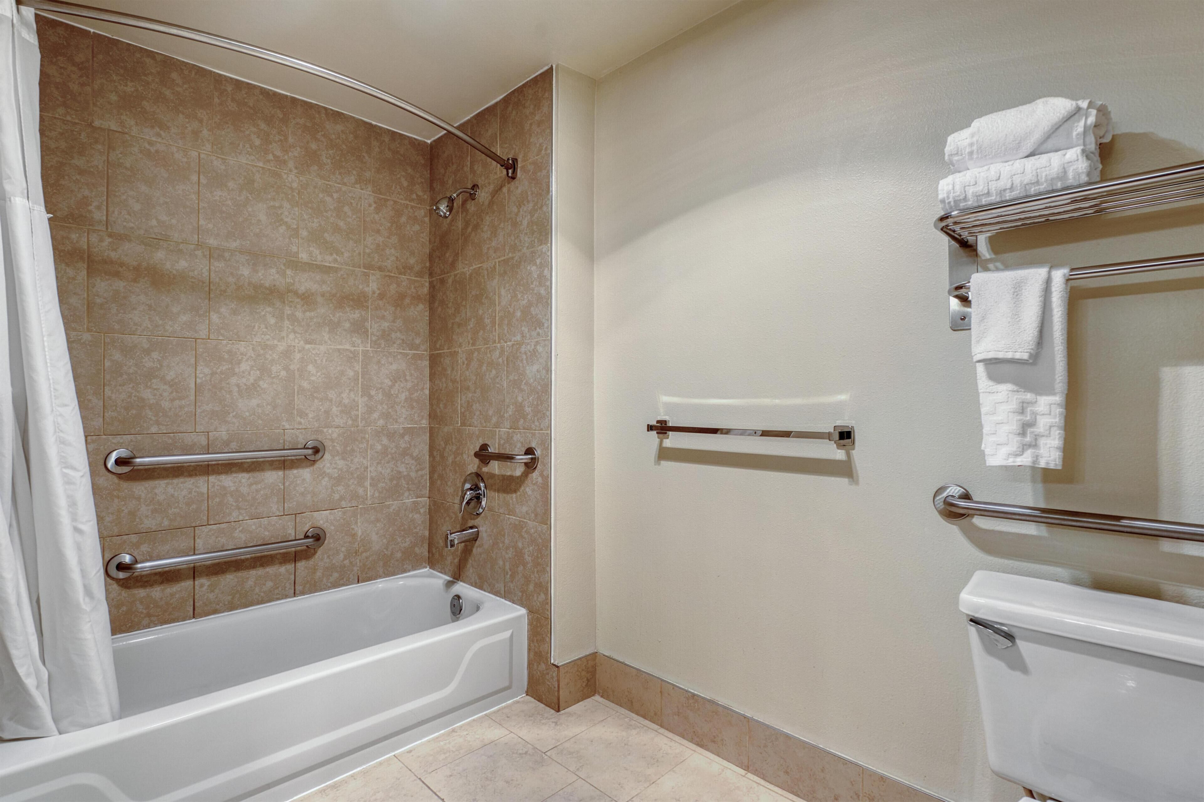 A bathroom with a bathtub, a toilet, and a shower area.