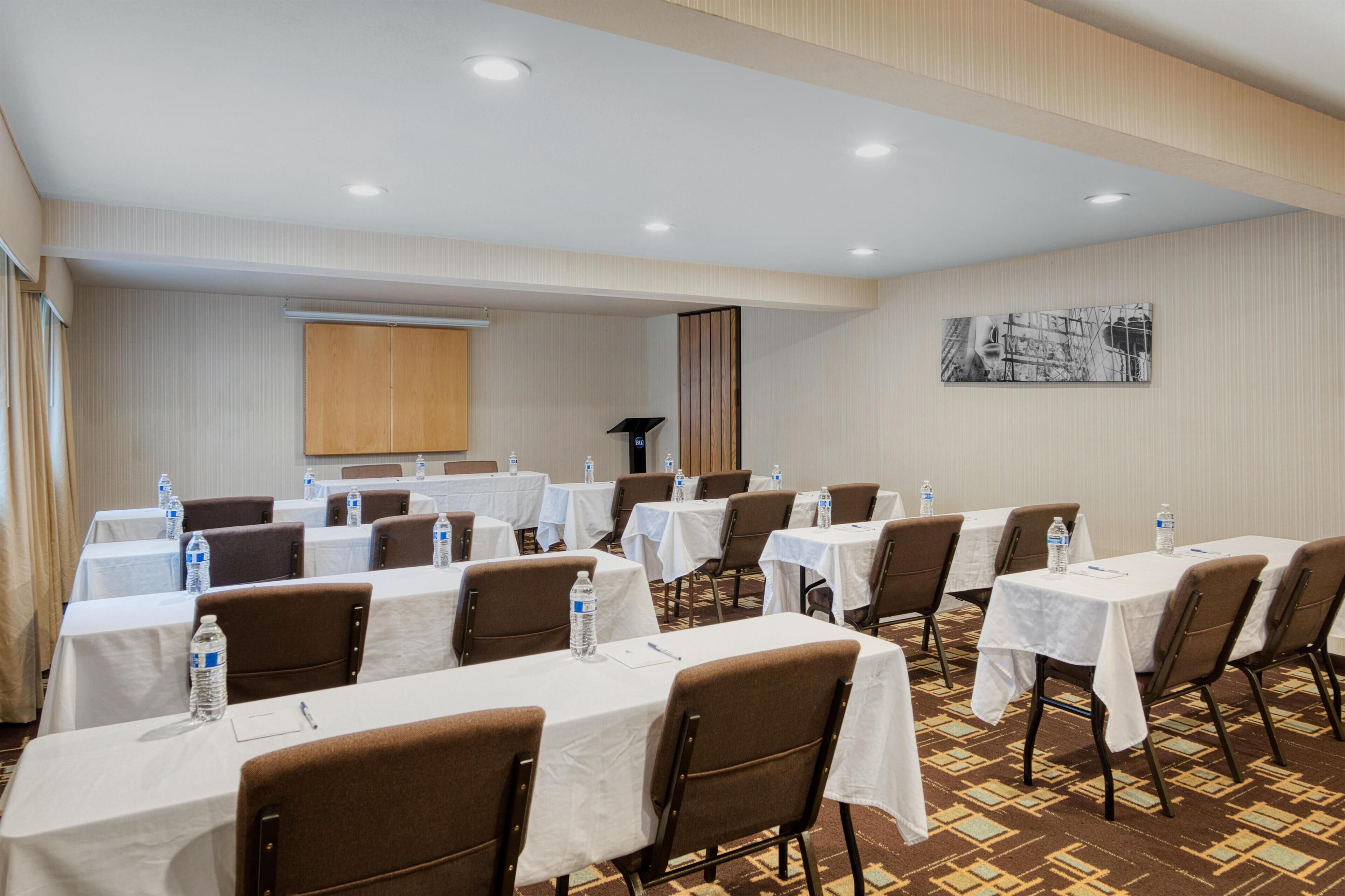 A conference room with multiple tables, chairs, and water bottles.