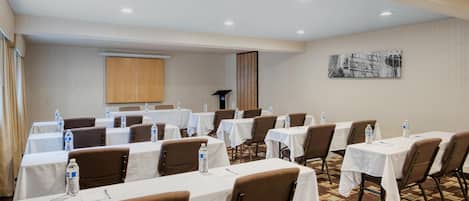A conference room with multiple tables, chairs, and water bottles.