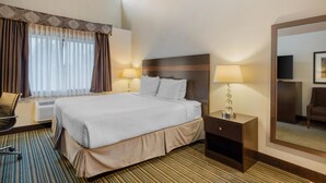 A hotel room with a large bed, two bedside lamps, a chair, a desk, and a mirror. - Best Western Alderwood (Lynnwood)