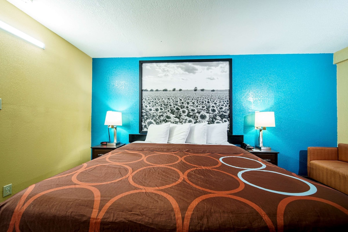 A hotel room with a bed, two bedside lamps, a nightstand, and a framed picture on the wall.