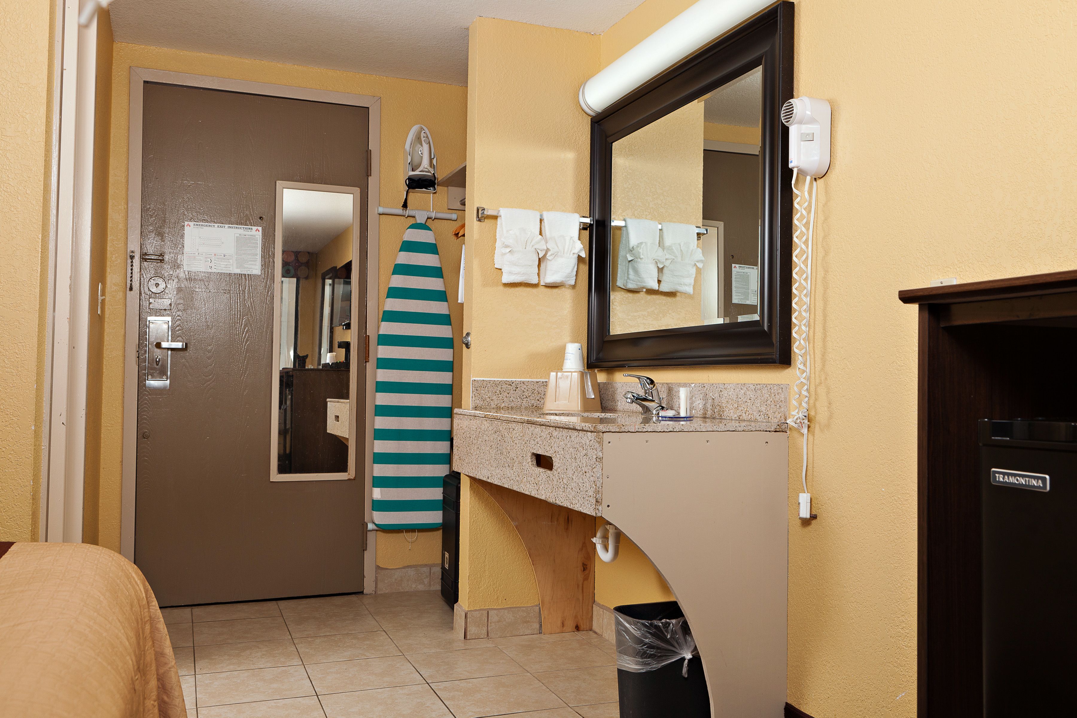 A bathroom with a sink, mirror, towel rack, and a door leading to another room.