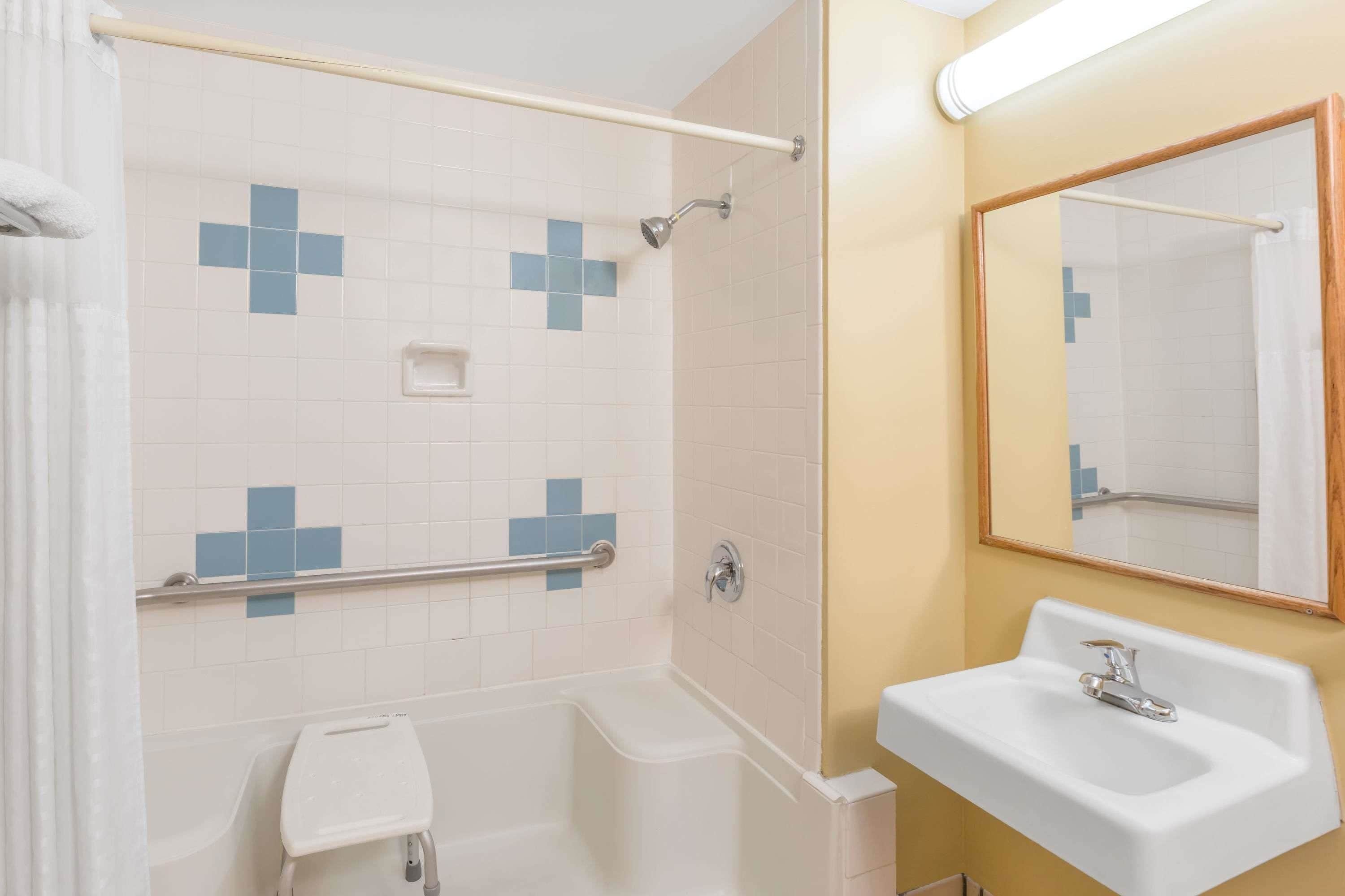Un bagno con una vasca, una doccia, un lavandino e uno specchio.