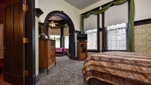 Un dormitorio con una cama grande, armario de madera, arco de entrada y televisor.
