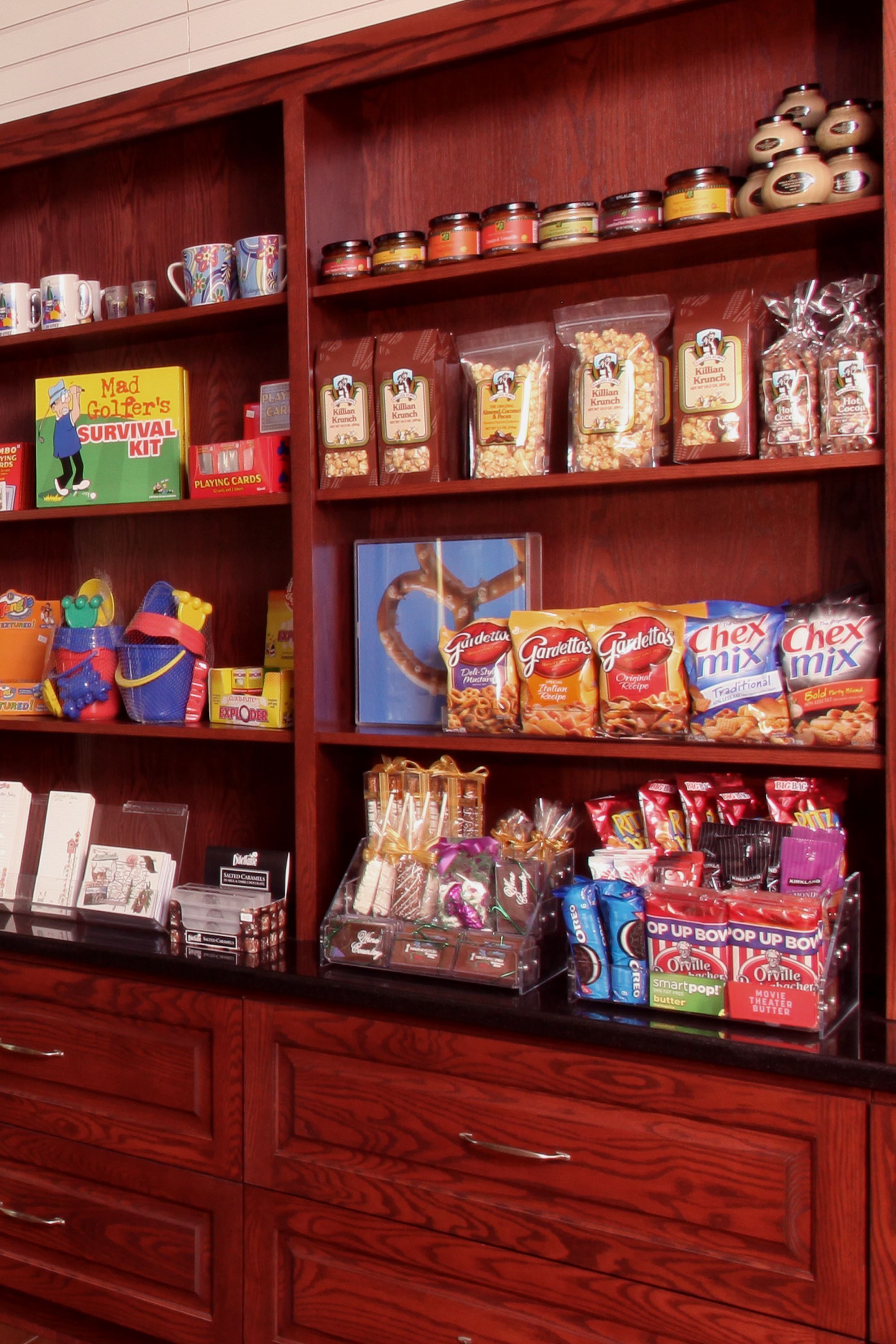 A shelf stocked with various snacks and food items, including bags of chips, cookies, and jars of spreads.