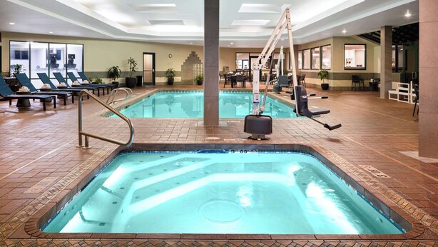 An indoor swimming pool with lounge chairs, a hot tub, and a staircase leading to an upper level. - Hampton Inn Richland/Tri-Cities (Richland)