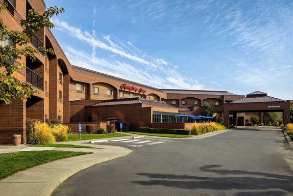 A Hampton Inn hotel with a brick facade, a welcoming entrance, and a clear sky.