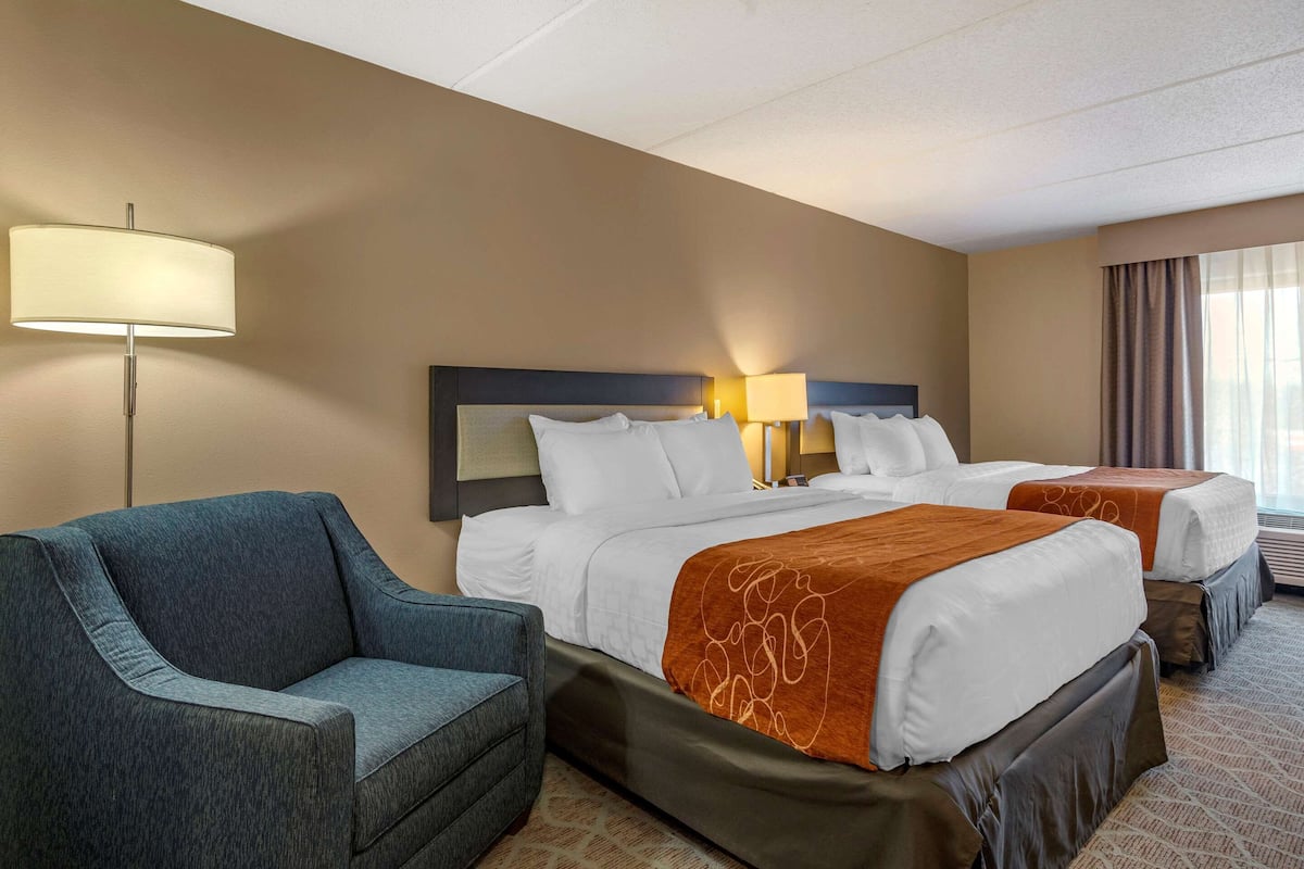 Ein Hotelzimmer mit einem großen Bett, zwei Nachttischen, einem Sofa und einer Lampe.