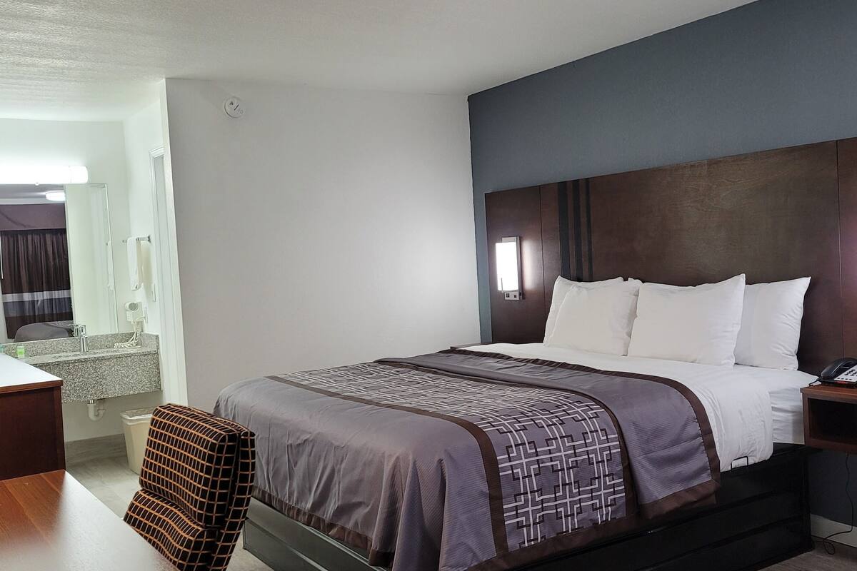A hotel room with a bed, bedside table, and a desk with a chair.