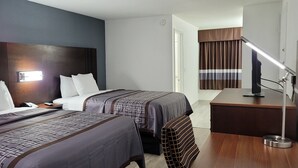 A hotel room with two beds, a desk, a chair, a desk lamp, and a television. - Key West Inn - Boaz (Boaz)
