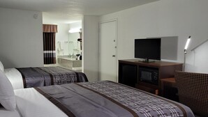 Hotellihuone, jossa on kaksi sänkyä, televisio, työpöytä ja taustalla näkyvä kylpyhuone.