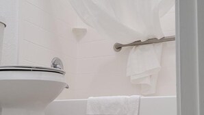 A bathroom with a toilet, a bathtub, and a shower curtain. - Key West Inn - Boaz (Boaz)
