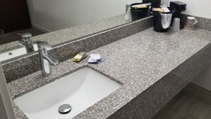 A bathroom with a granite countertop, a white sink, and a mirror. - Key West Inn - Boaz (Boaz)
