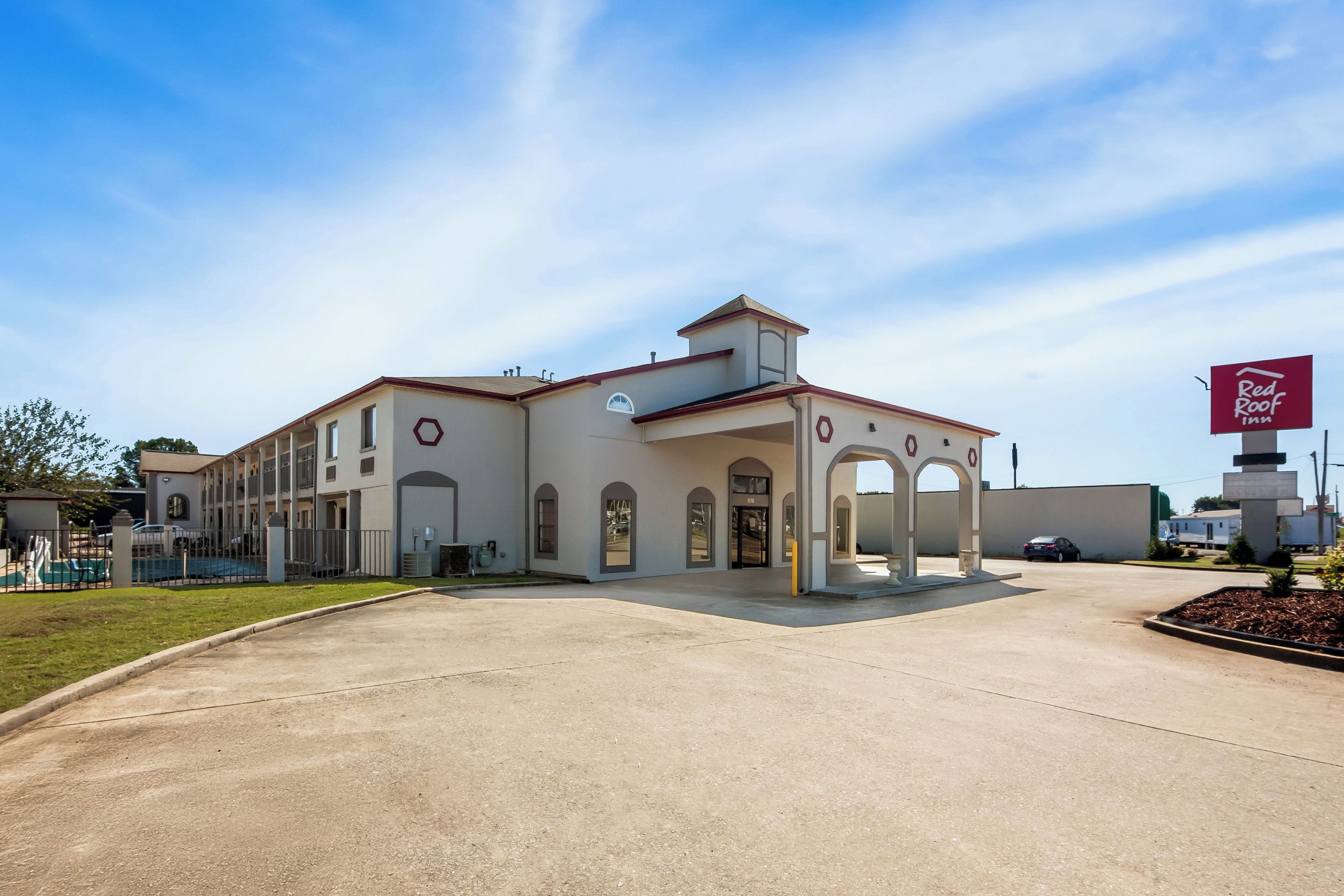 A Red Roof Inn with a central entrance, multiple balconies, and a clear sky.