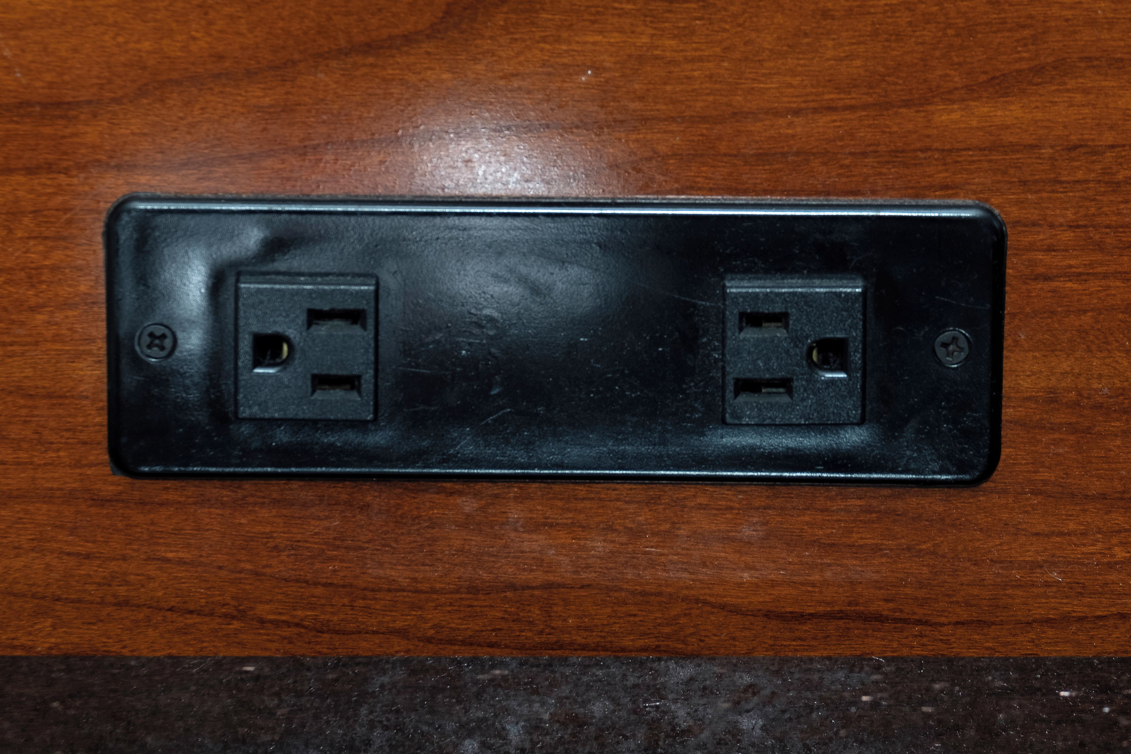 A black electrical outlet on a wooden surface.