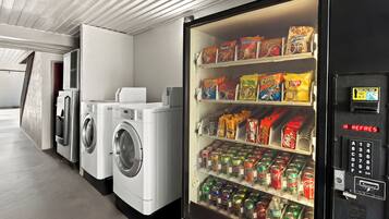 A laundromat with washers and dryers, and a vending machine stocked with snacks and drinks.