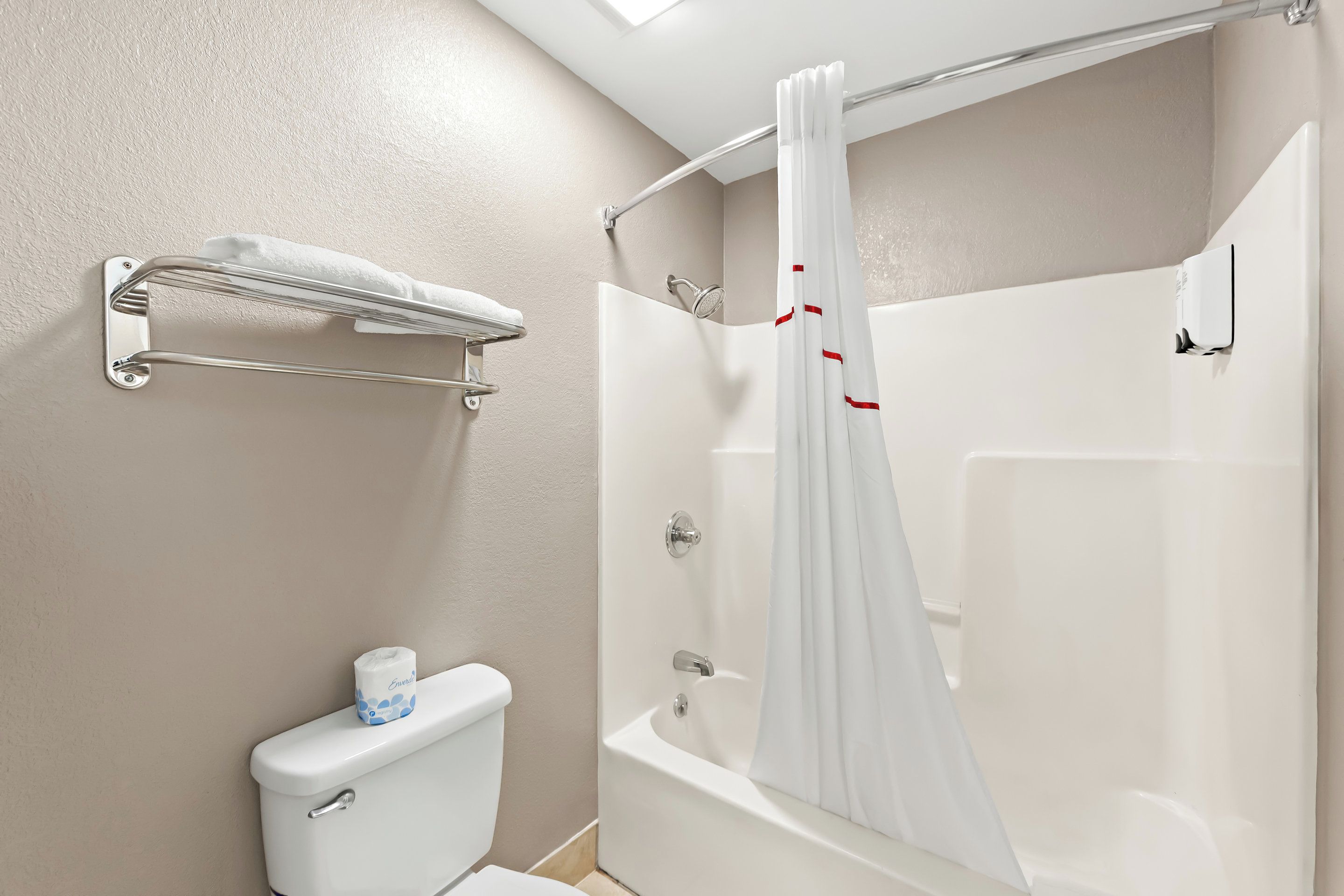A bathroom with a toilet, a shower, and a towel rack.