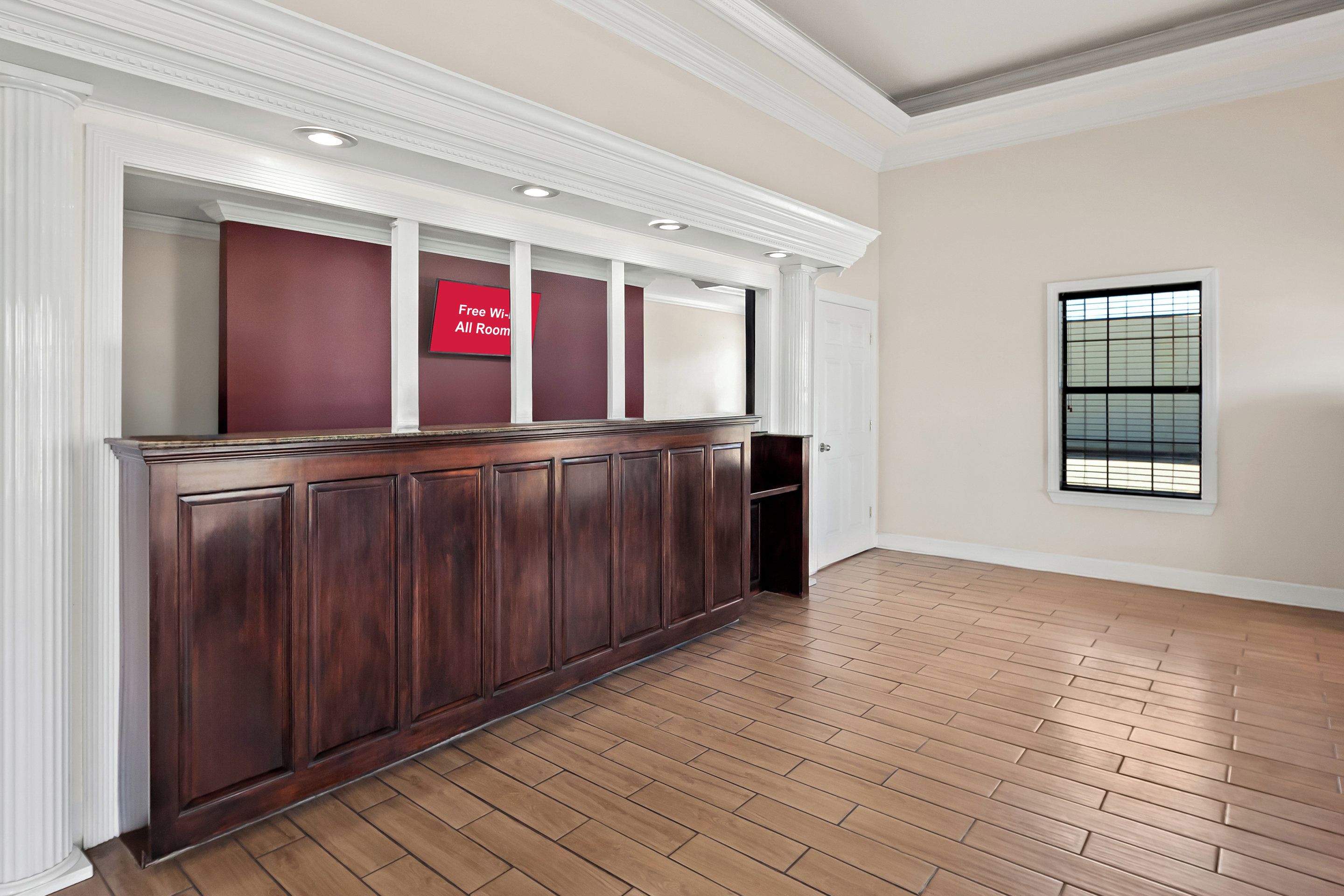 A reception area with a dark wood panel, a red sign, and a window with blinds.